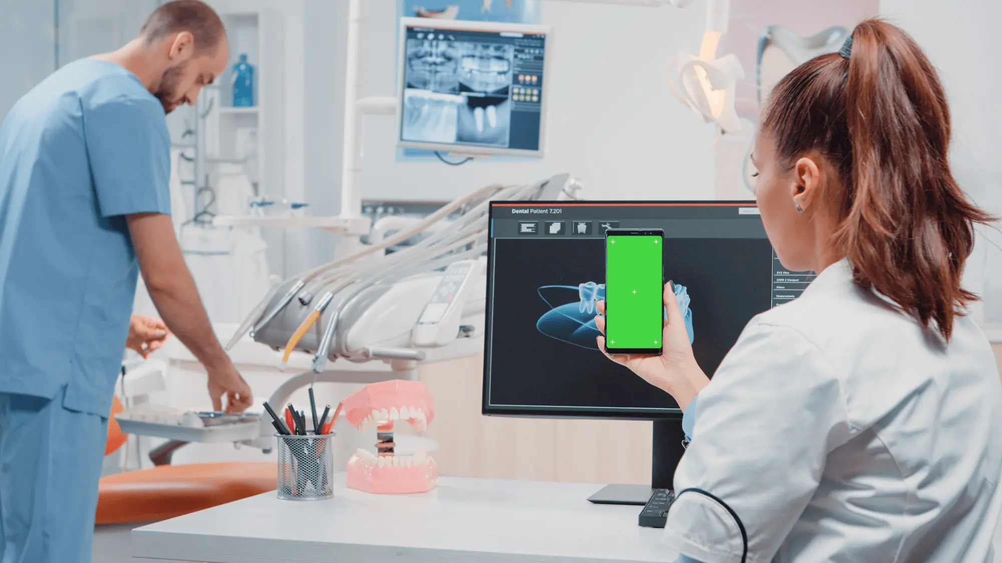 Impresión 3D en Odontología: Revolución en Tratamientos Dentales 4 woman looking green screen mobile phone stomatological care dentistry office orthodontist holding smartphone with chroma key mockup template display teethcare - Impresión 3D en Odontología: Revolución en Tratamientos Dentales 2026